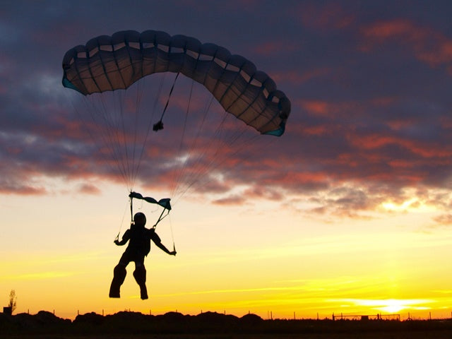 Person parachuting against a sunset sky